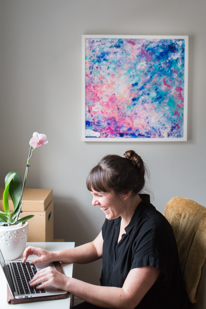 Durham massage therapist Megan Rowell working in her office with Courtney Potter's abstract pink and blue painting on her walls.