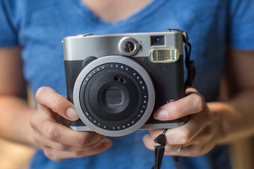 Close-up branding photo of a woman's hands holding a polaroid camera.