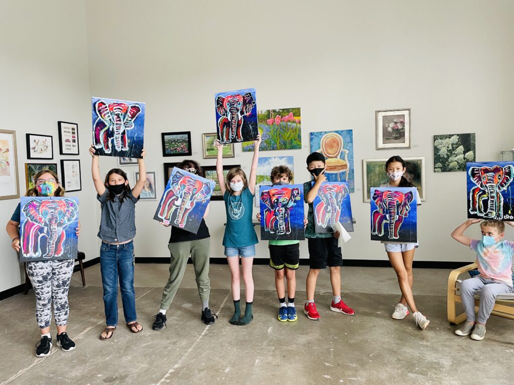 Art campers pose with their original canvas paintings of elephants